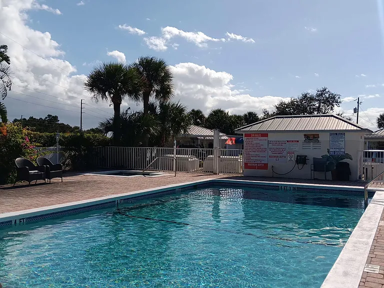 Resort-style outdoor pool area with paver deck, lounge seating, and palm landscaping for relaxing and entertaining.