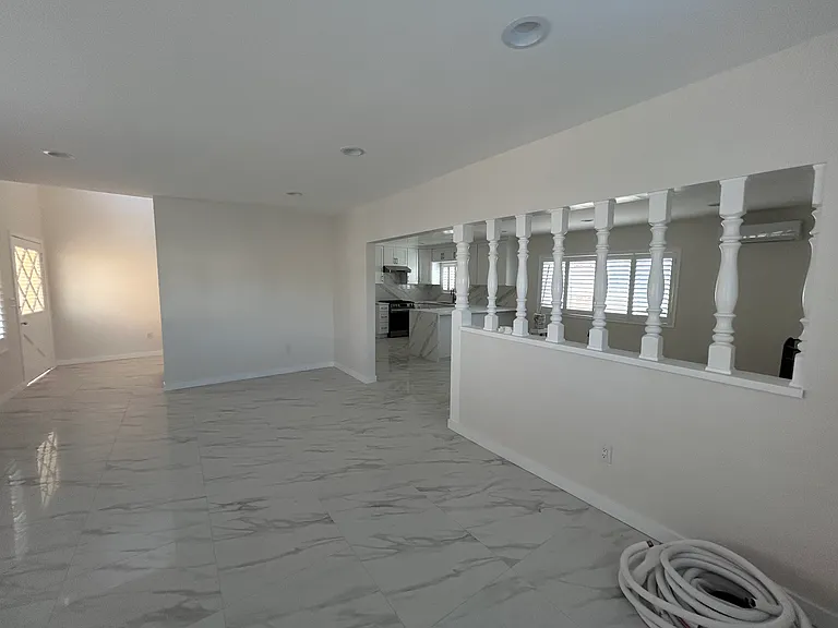 View from living room. Front entrance is to the left. Kitchen and fireplace (nonfunctional) is to right.