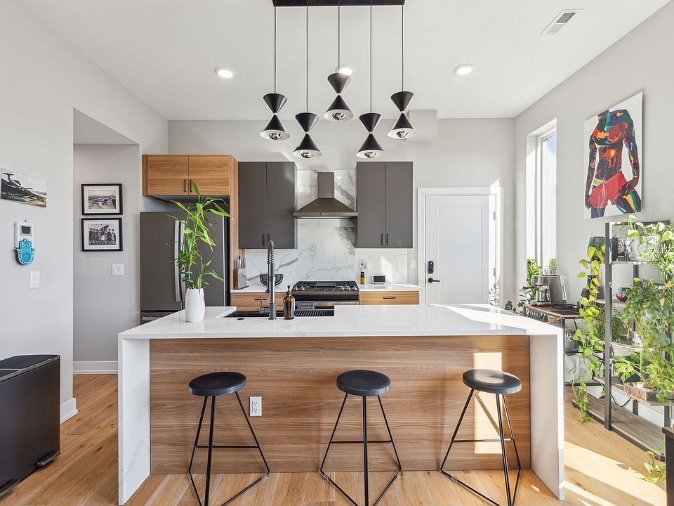 Custom kitchen with marble tiled backsplash, GE appliances, quartz countertops and waterfall island.