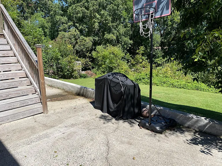 Yard slopes down and there's a back patio at the lower level. (grill and hoop not included)