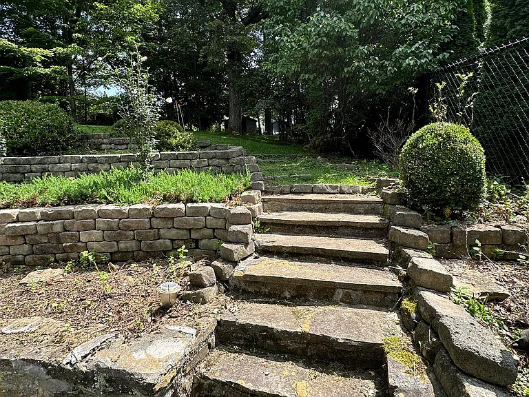 stone steps lead from patio up to yard area