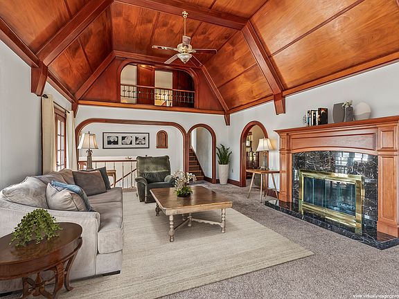 Balcony off the attic looks out on the mahogany vaulted ceilings and cozy wood-burning fireplace. Note partial virtual staging