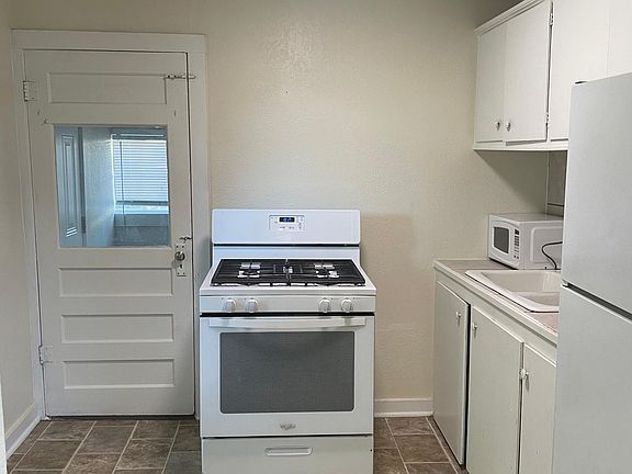 Kitchen with fridge and gas stove, laundry room/storage is off of kitchen as well as a back door