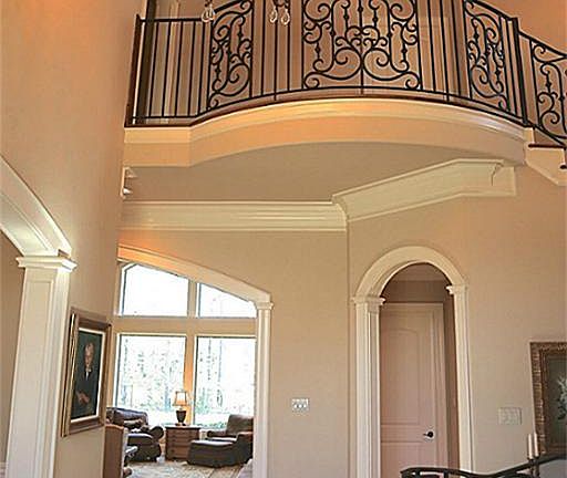 Grand two story foyer entrance with a sparkling chandelier. Staircase has custom wrought iron featur
