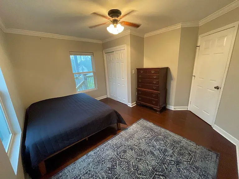 Spacious primary bedroom with tall dresser, closet space, and patterned area rug.