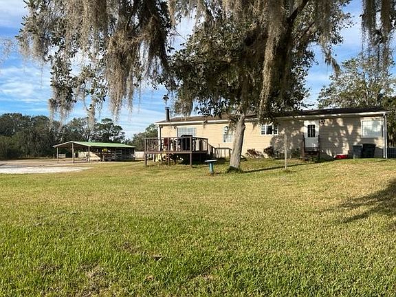 Rear of residence with deck and carport in background.
