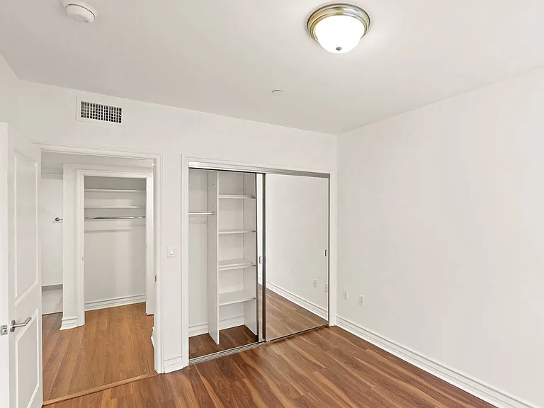 Bedroom with Mirrored Closet and Hardwood Flooring