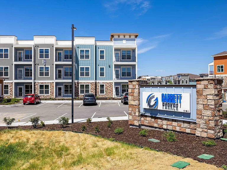 A stone monument sign marks the entrance to Garrett Parker, an apartment community at 15511 Belford Avenue in Parker, CO.