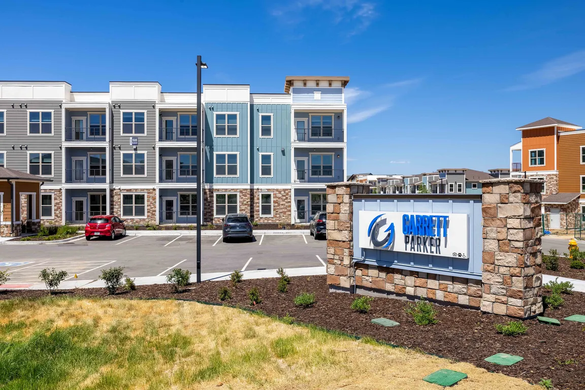 A stone monument sign marks the entrance to Garrett Parker, an apartment community at 15511 Belford Avenue in Parker, CO.