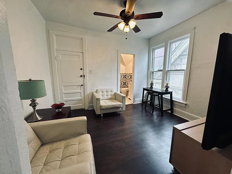Living room view. Entry door on the left, bathroom door right. Laminate wood floors.
North facing window