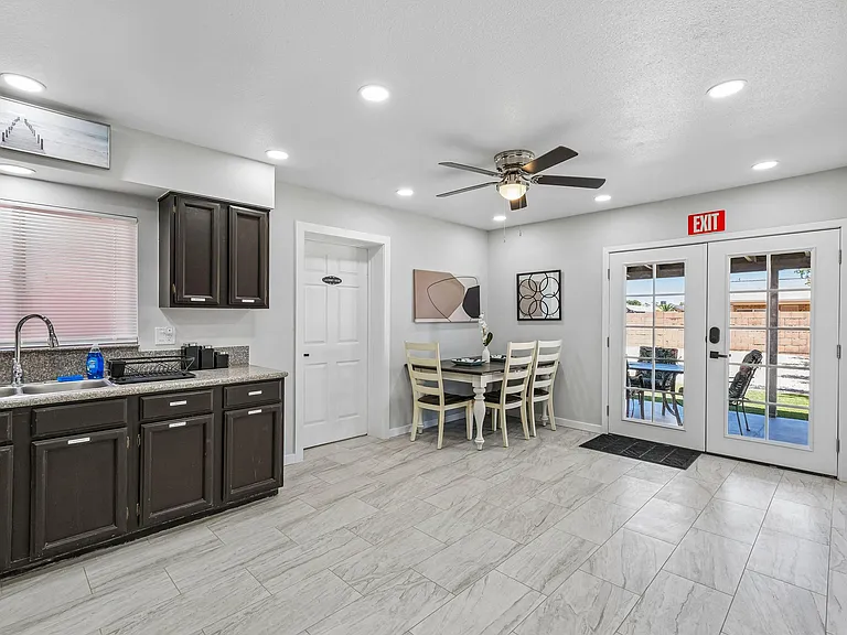 Open kitchen and dining nook with ample cabinetry, granite-look counters, and French doors leading to the patio.