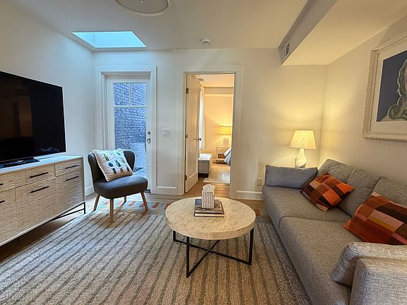 Large sunny living room with all new, comfy furnishings (shows skylight and door to private rear patio)