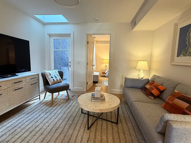 Large sunny living room with all new, comfy furnishings (shows skylight and door to private rear patio)