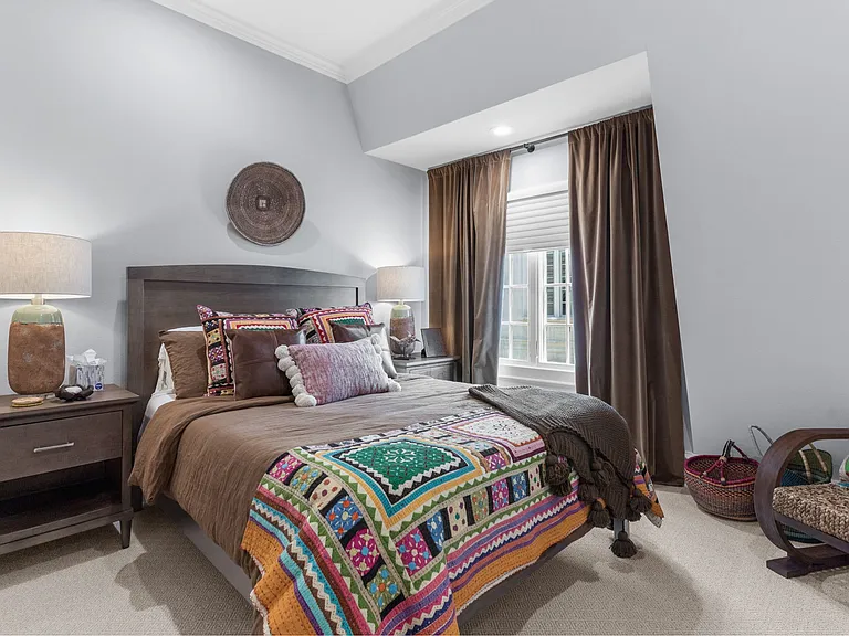 This fourth-floor guest bedroom features a queen bed, abundant natural light, and colorful bedding and decor.