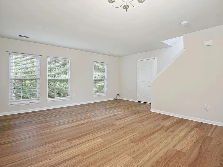 Overview of the entrance into the unit and the living area from the dining area. The stairs to the upper level are visible on the right.