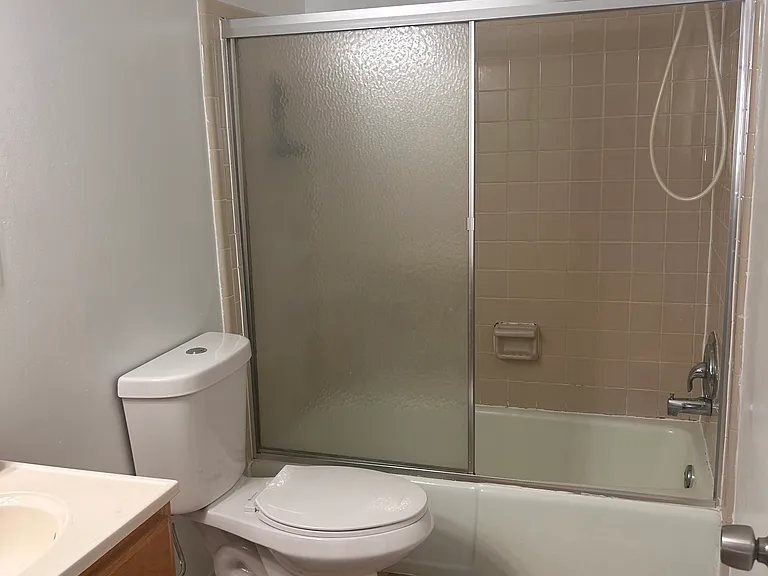 Full bathroom has tub and shower combination with sliding door.