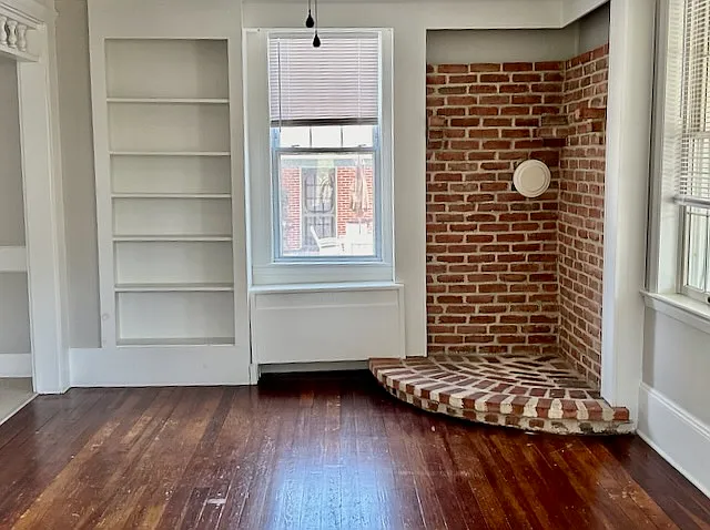 Living room with hardwood floors, built in and accent brick corner - perfect for display, decor or electric stove. - 10 Queen Rd