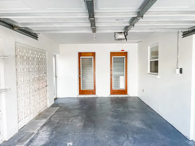 Very clean oversized one-car garage with painted floor. One door leads into laundry room/half bath, and the other into dining room area.