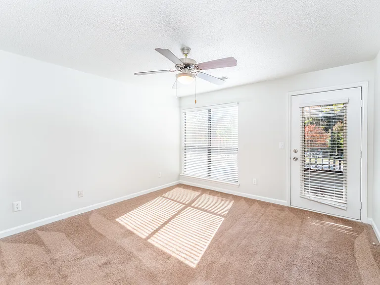 Bright Living Room with Fresh Carpeting and Ceiling Fan Connected to a Private Balcony - Gold Interior
