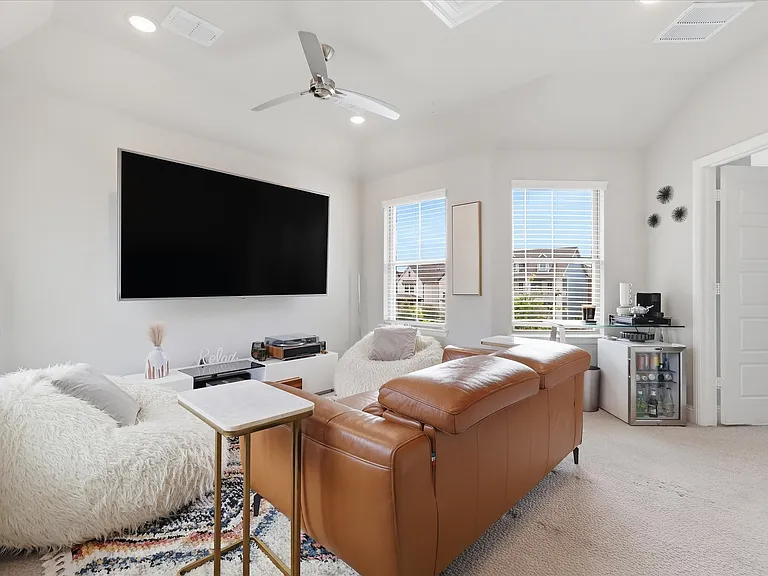 Upstairs media room with high ceiling with recessed lighting and a ceiling fan.
