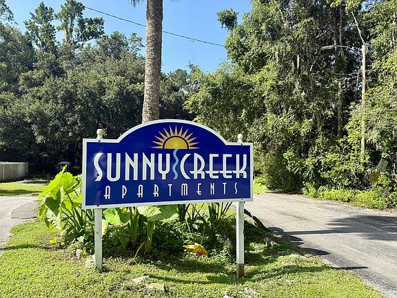 Inviting entrance sign of Sunny Creek Apartments surrounded by lush greenery, promising a tranquil living experience.