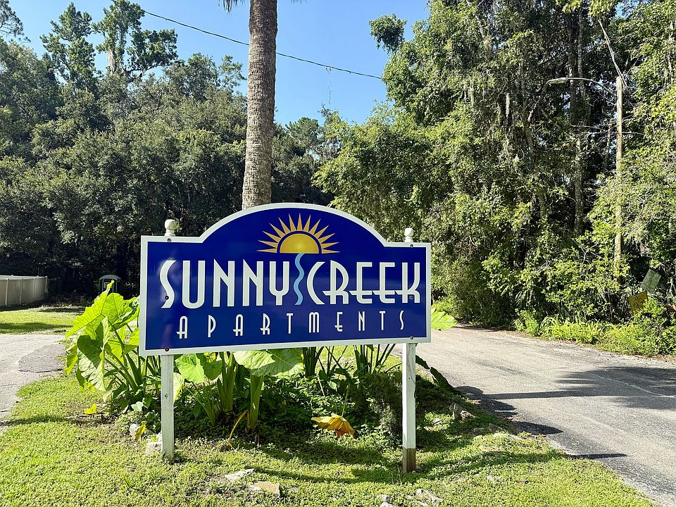 Inviting entrance sign of Sunny Creek Apartments surrounded by lush greenery, promising a tranquil living experience.