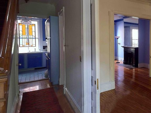 Entering Front Door, generous stairs to the left, kitchen ahead, living room to the right, with the dining room visible thru a second set of pocket doors.