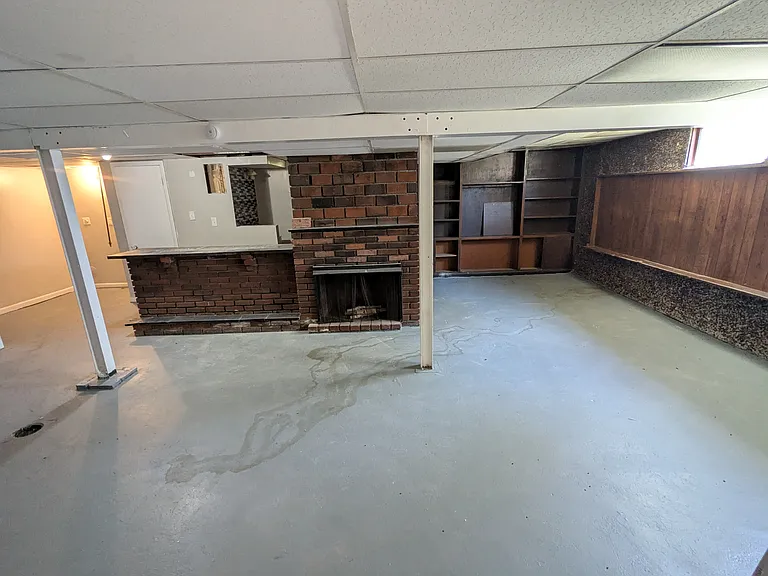 Basement laundry area, bar, and open space. Fireplace does not work.