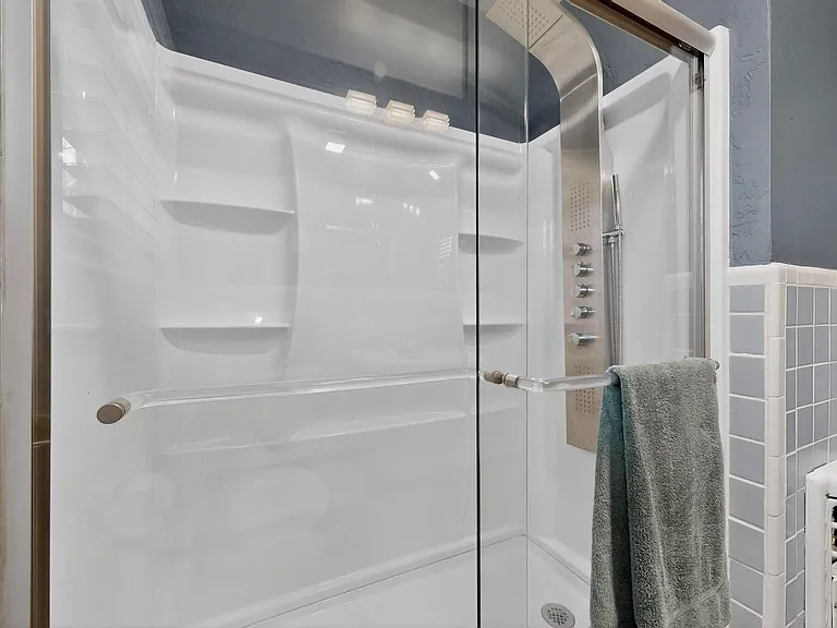 Stylish bathroom showcasing shelves on the wall and an overhead and body shower enclosed in a glass door