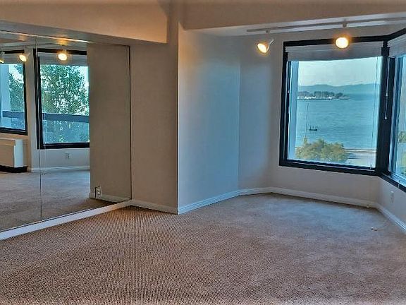 Living/dining room, mirrored wall, view. Railing to the right is on the balcony. Below that is heater with AC. Double pane windows shut out the noise and cold.