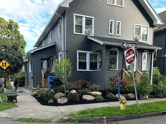 Front corner of building after recent landscaping was completed. Additional landscaping has been installed, including a row of blue perennial flowers between the sidewalk and the building in front of the available unit.
