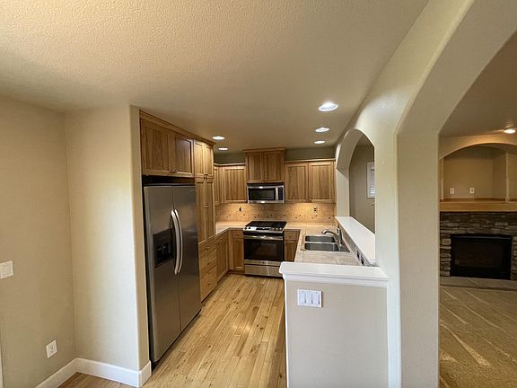 Kitchen with stainless appliances, tile counters.