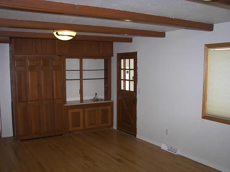 Family Room looking south to wet bar and cabinets. Door is