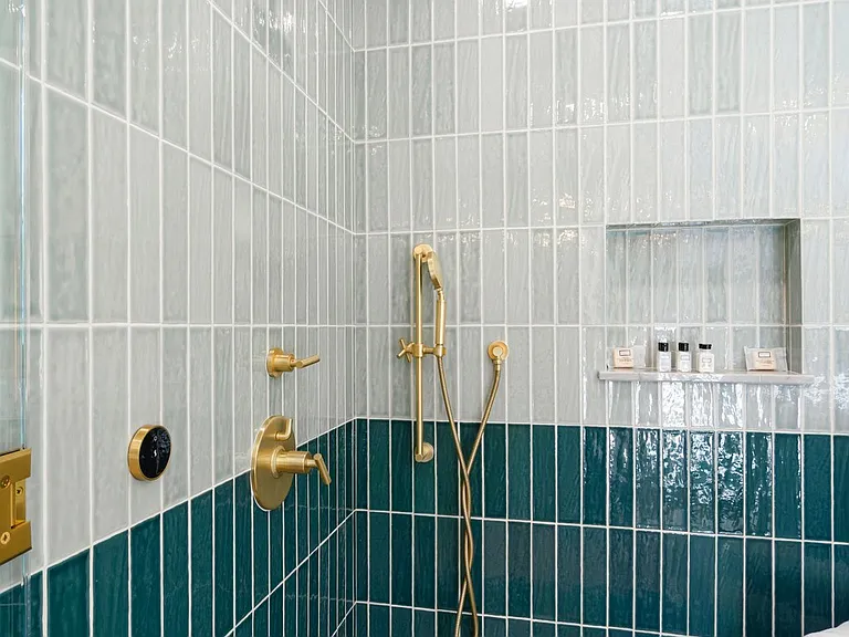 Step into a bold shower wrapped in deep green tile and luxe brass.