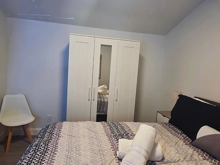 Beautiful bedroom with bedside lamps, an accent chair and a spacious closet