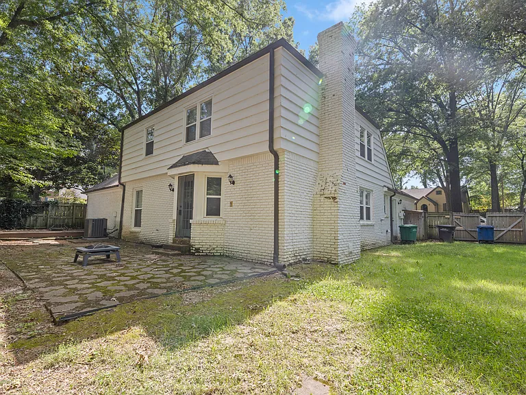 Classic two-story exterior with brick chimney, stone patio, and beautifully maintained yard _ the complete package awaits you!
