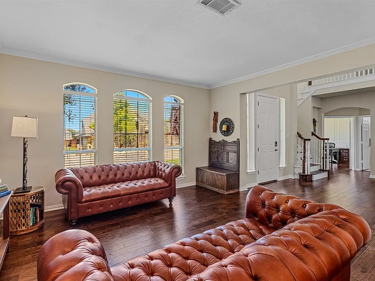 Living area featuring wood-finish flooring, three arched windows with blinds, and white trim