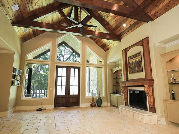 Family room with wall of windows, wood and beams on ceiling is open to kitchen area