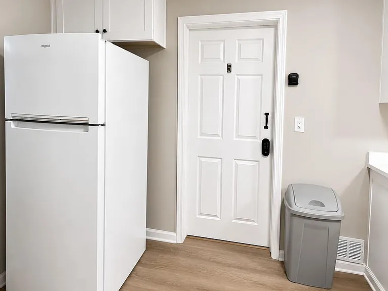 Kitchen corner features a full-size refrigerator, overhead storage, and durable flooring near the entry for easy access.
