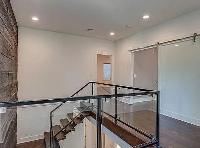 Stairs to the 2nd floor lead to a glass barn door into the media room/entertaining room and a bedroom on the left.