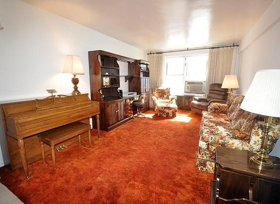 Large Sunny living room has covered hardwood floors and opens to the dining foyer.