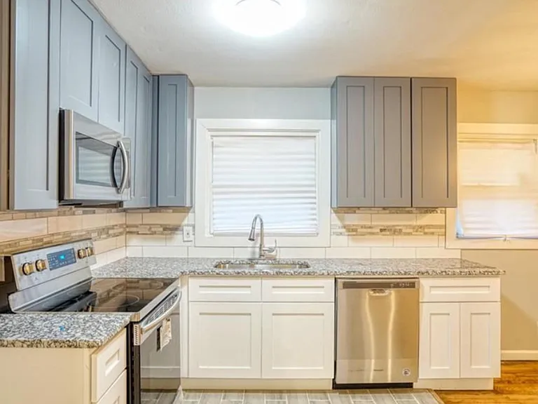 Efficient kitchen with shaker cabinets, granite-look counters, stainless appliances, and a window over the sink.