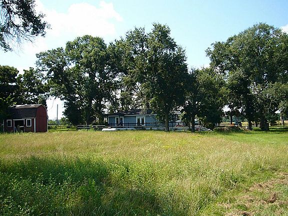 Distant view of home showing storage building and trees.