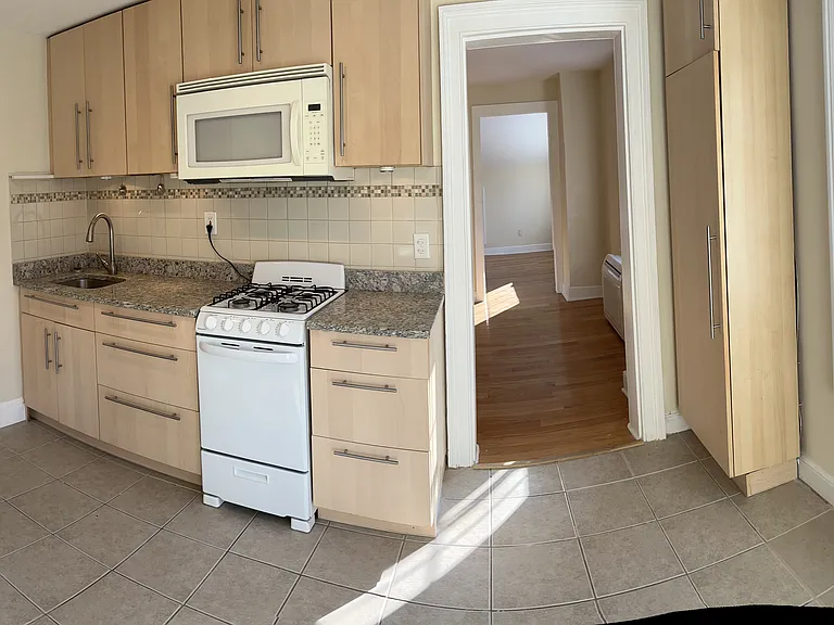 Sunny eat-in kitchen with granite countertops, ample cabinetry, and an oversized window overlooking a peaceful wooded view. Functional layout with gas range and microwave_perfect for cozy meals and enjoying natural light year-round.