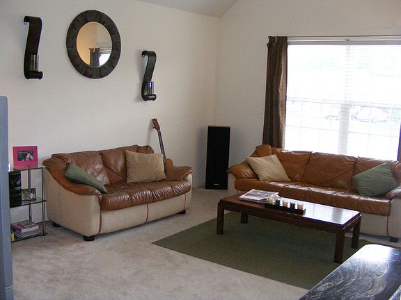 Living room with ceiling fan, vaulted ceiling, and small entrance foyer. 
