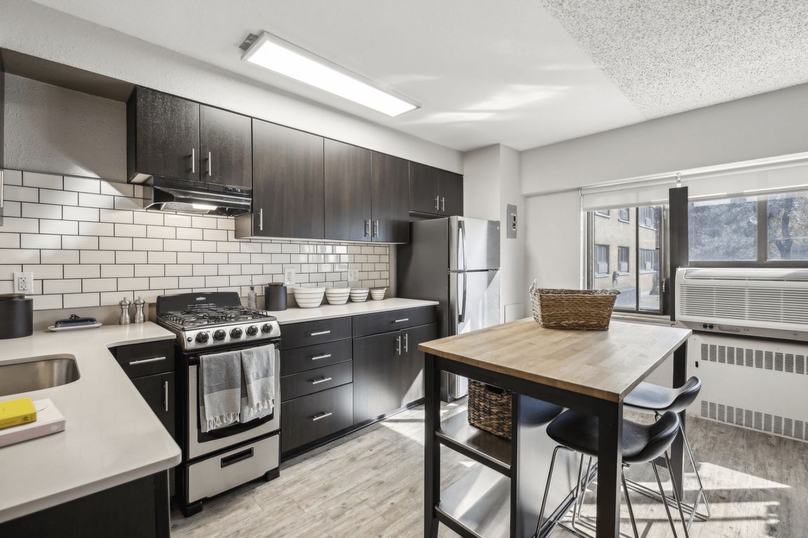 This kitchen features black cabinets and white appliances, as well as a wooden table