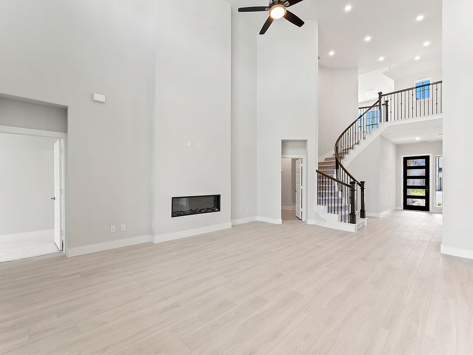 An expansive, high-ceiling living room features a cozy fireplace and excellent ventilation, creating an airy and inviting space perfect for relaxation and entertaining. Staircase opening into the living room.