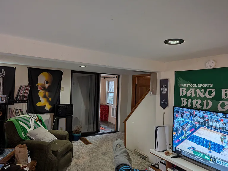 Large living room with sliding door to 3 season front porch with front bottom bedroom door and bottom of stairs in view.