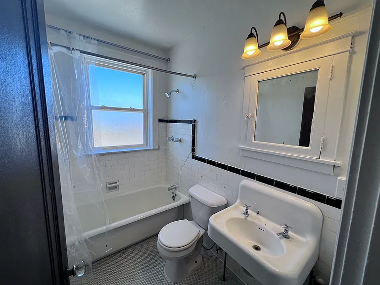 Vintage charm meets everyday practicality. Original tile details, a classic cast-iron sink, and built-in medicine cabinet add character to this bright bathroom, while the window provides natural light and ventilation.