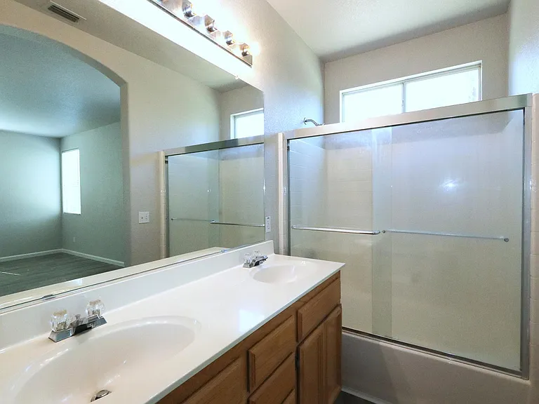 Master Bathroom with Dual Sinks, Vanity Lights, and Oversized Tub